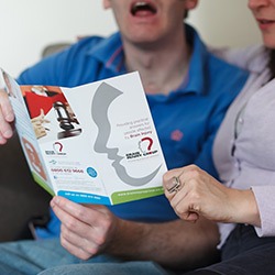 A man with a brain injury looks at a Brain Injury Group brochure on brain injury compensation claims with his carer