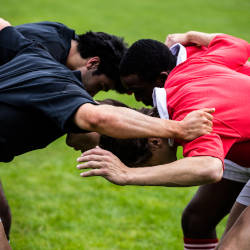 An image of rugby players locking heads about to engage in a scrum illustrating the head impacts and brain injuries in sport