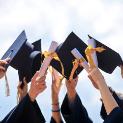 Graduation hats thrown into the air celebrating graduation from University illustrating how people with a brain injury can get funded support at University