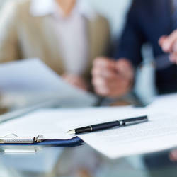A solicitor sits at a table with a couple as paperwork is visible in the foreground illustrating the role of the official solicitor