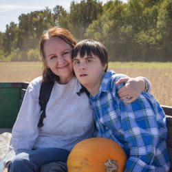 A mother and son with a brain injury sit on the back of a tractor trailer illustrating the difficulties of dealing with Mental Capacity and finances when your child reaches the age of eighteen.