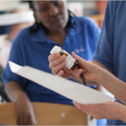 A care worker listens to the instructions regarding a bottle of tablets illustrating the difference between care and rehabilitation