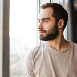 A man called Adam looks out of the window, illustrating our updated Adam's story about his criminal injuries compensation authority claim following a criminal attack