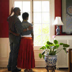 A couple hold each other while looking out of the window of their home illustrating Deprivation of Liberty Safeguards