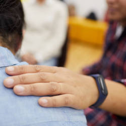 A hand on a shoulder illustrating our article on getting support from charities