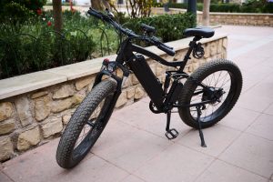 E-bike parked up by a stone wall in a a city.