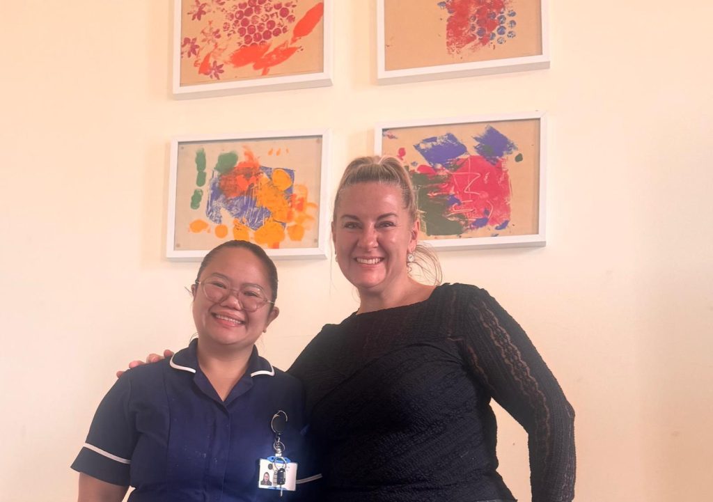 Two women smiling together, one of them in a nursing uniform
